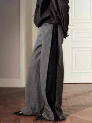 Side close-up of artisan stitch detail wide-leg streetwear pants showing gray fabric, black exposed side seams, and relaxed two-tone panel construction