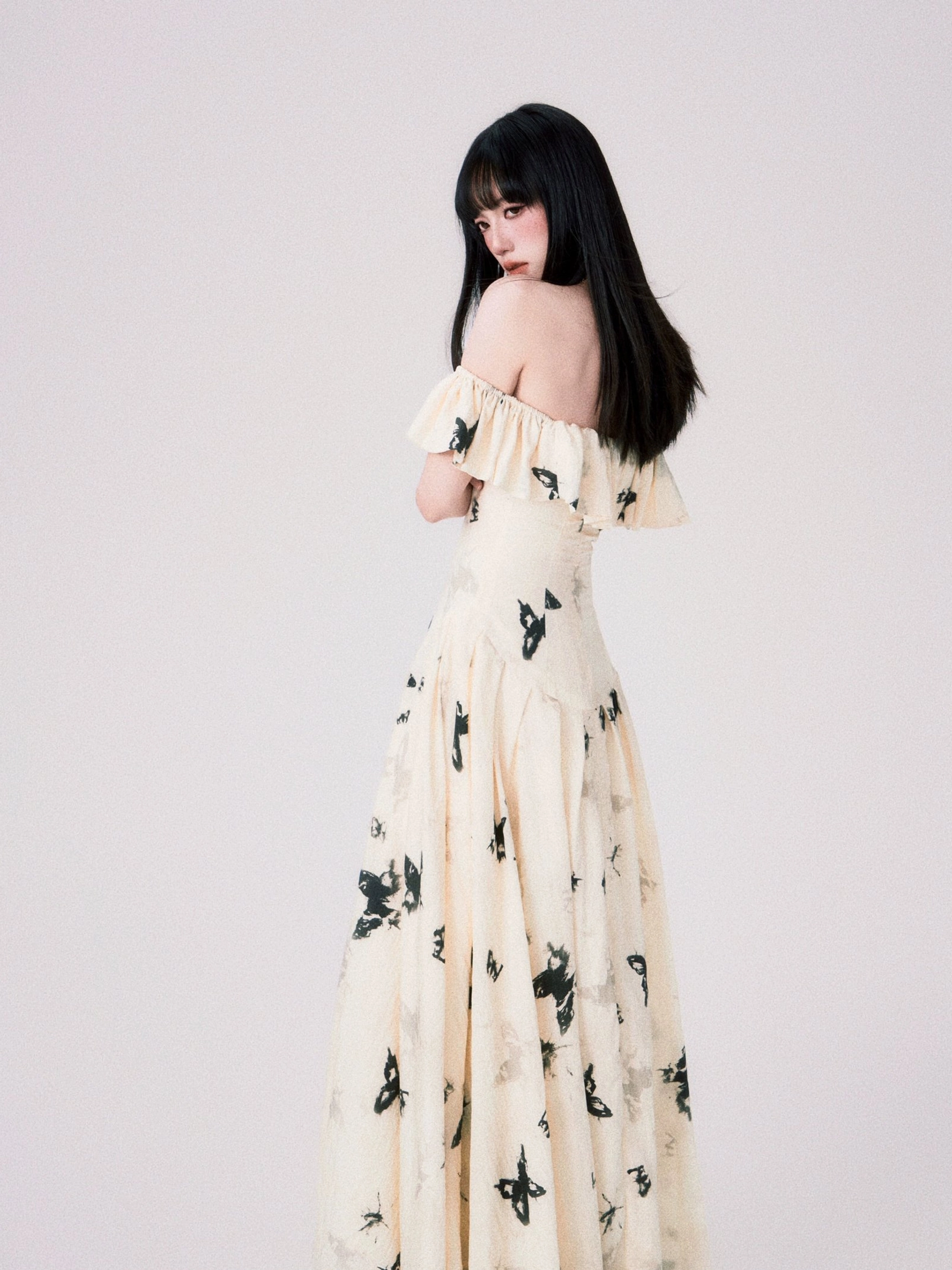 Artistic black butterfly print on cream off-shoulder ruffle dress close-up