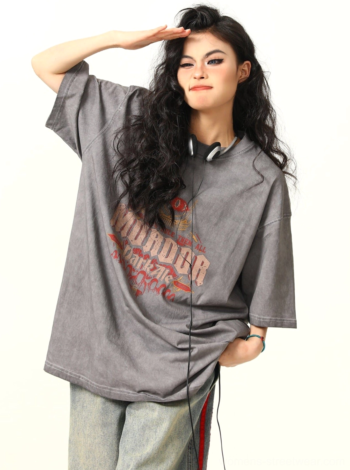 Three-quarter side view of a woman styling a faded ash gray MORDOR graphic T-shirt with relaxed drop shoulder streetwear proportions