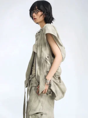 Female model wearing an ash gray oversized hooded utility vest in side profile with a draped sleeveless silhouette and large cargo pocket