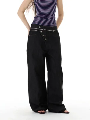 Front view of black asymmetric button placket wide-leg denim jeans styled with a striped cropped tank top in a minimalist studio