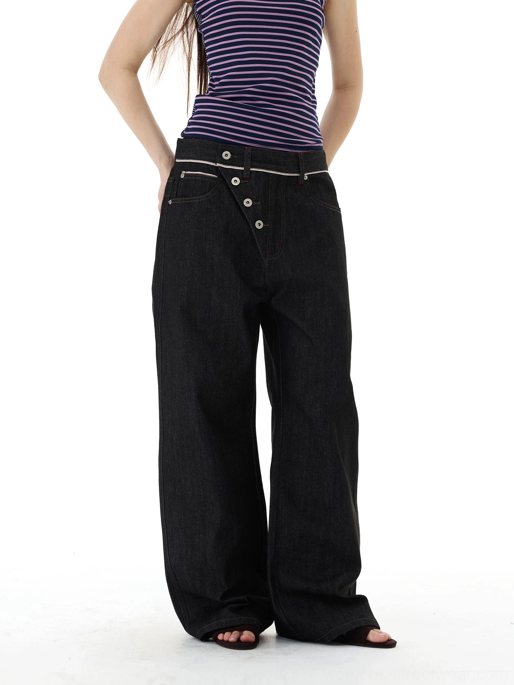 Front view of black asymmetric button placket wide-leg denim jeans styled with a striped cropped tank top in a minimalist studio