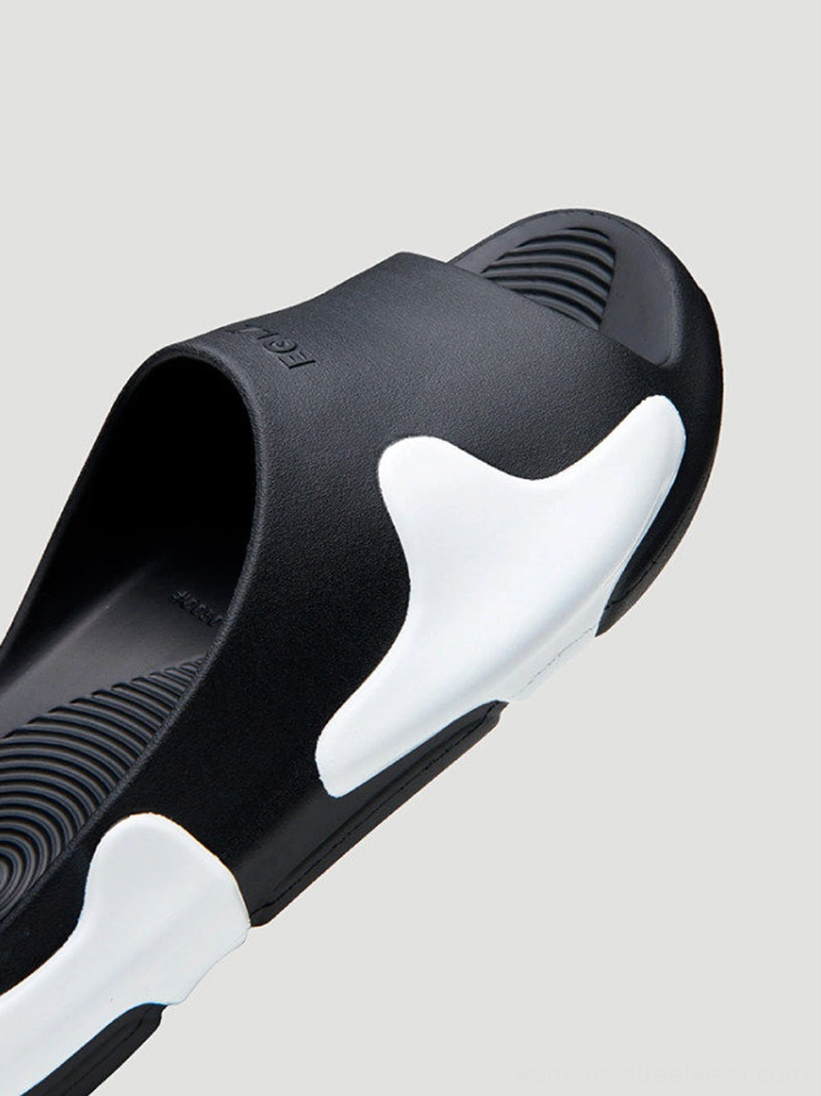 Close-up of asymmetric colorblock cloud cushion slide sandal showing embossed upper detail and open toe silhouette
