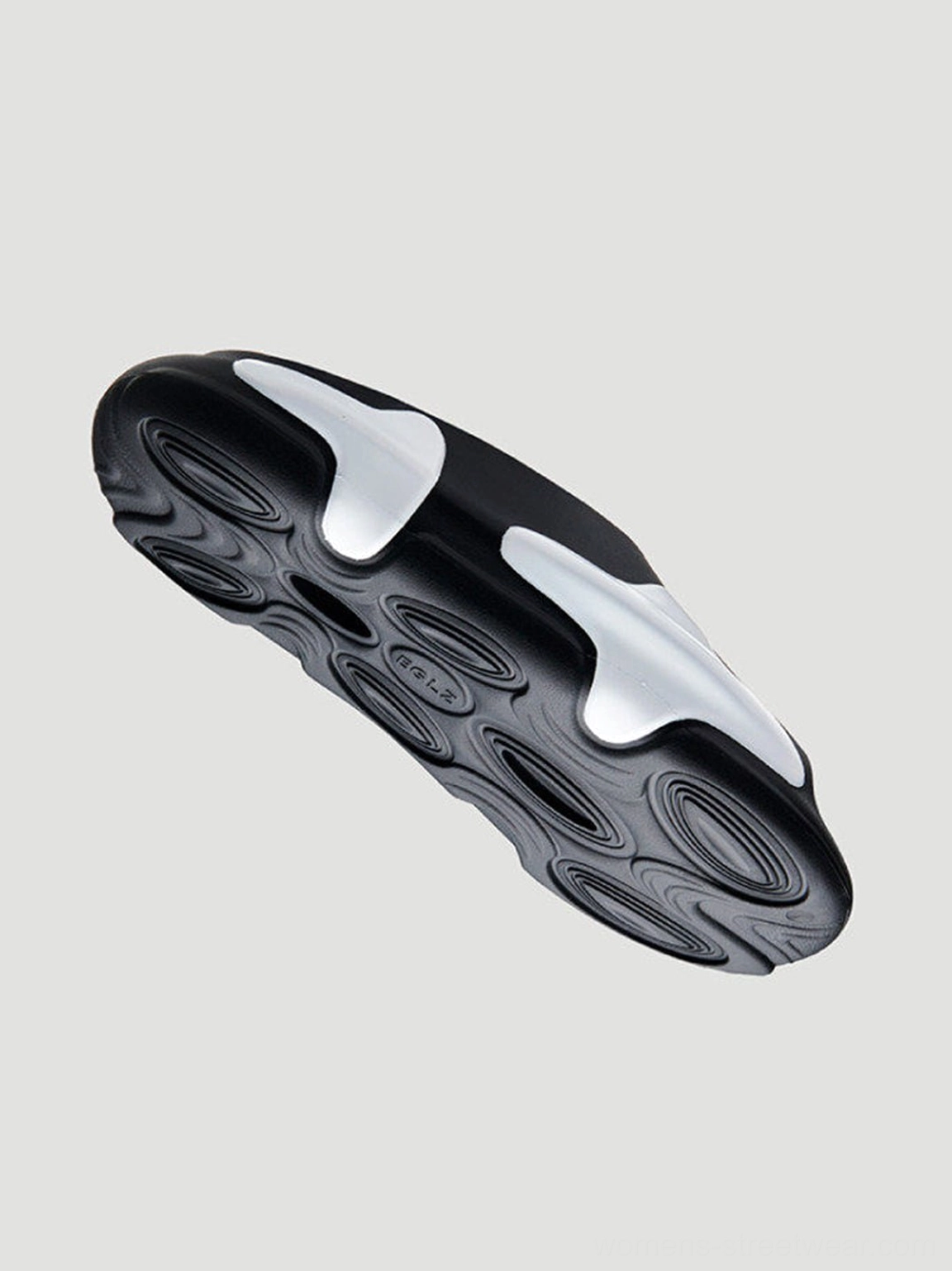 Bottom view of black and white asymmetric colorblock cloud cushion slide sandal showing sculpted wave outsole tread