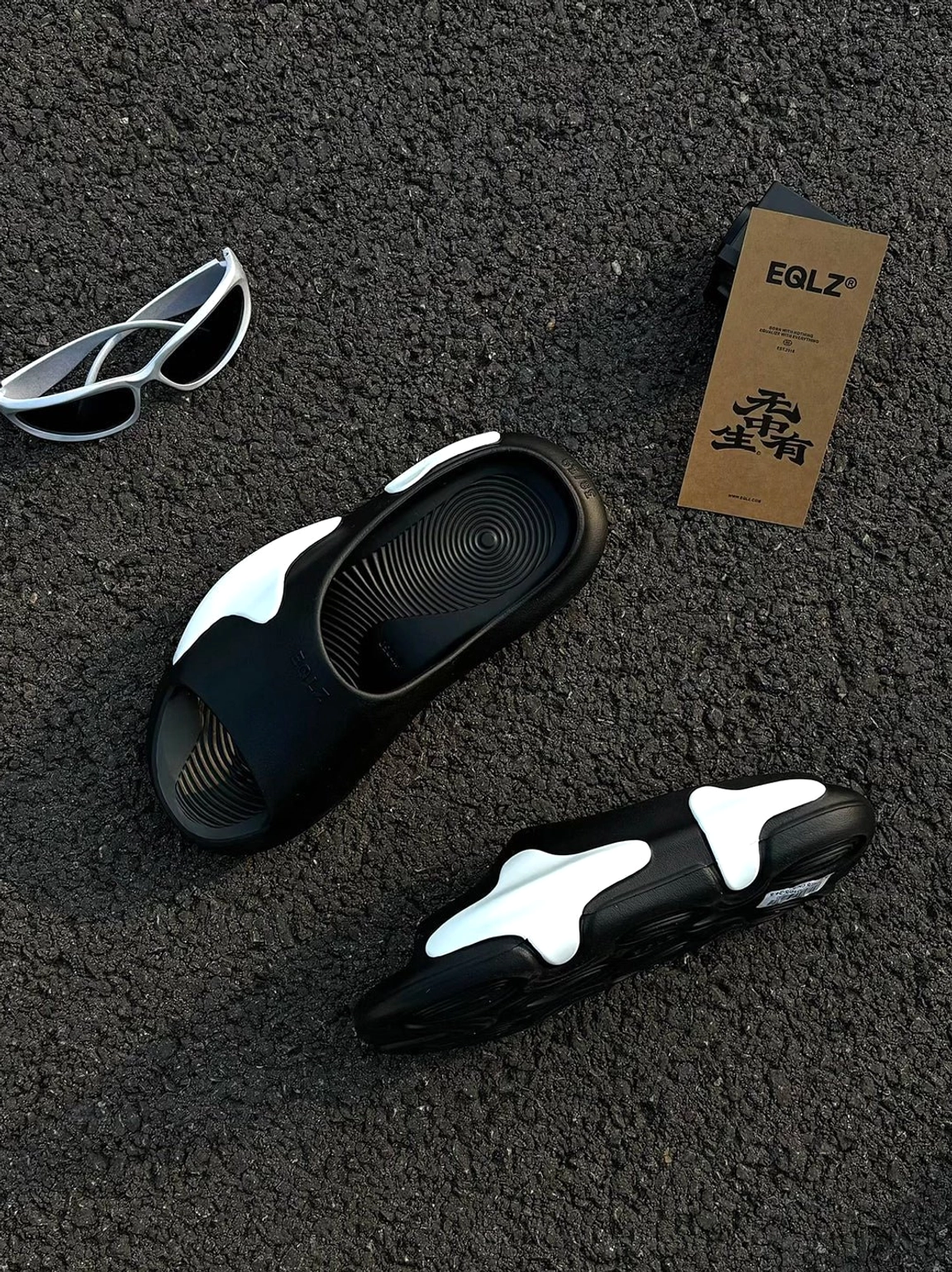 Pair of black and white asymmetric colorblock cloud cushion slide sandals showing open toe upper and textured footbed