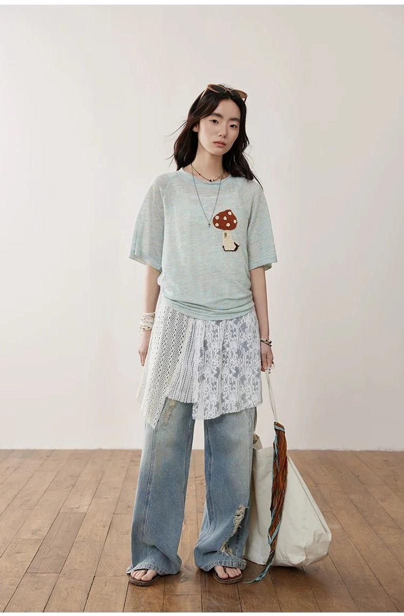 Asymmetric crochet lace camisole worn over a mushroom print tee with ripped jeans, sunglasses, and a large canvas tote bag