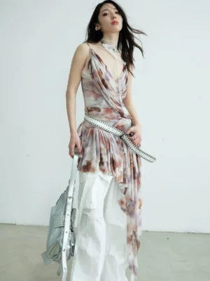 Watercolor tie-dye asymmetric draped fringe cami top with deep V neckline and pleated hem styled with white wide-leg pants