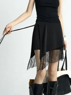 Black asymmetric lace hem wrap mini skirt styled with black camisole and tall biker boots front three quarter view