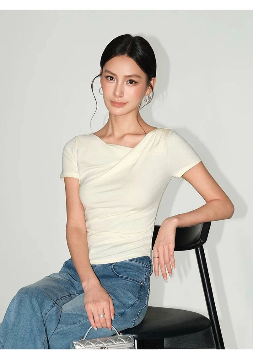 Cream asymmetric ruched slim fit top styled casually with denim jeans and a silver quilted handbag