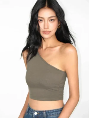 Olive green asymmetric one-shoulder stretch knit crop top paired with blue denim jeans in studio