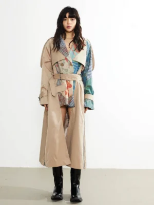 Front full body view of asymmetric patchwork belted khaki trench coat with artistic print panels, waist belt, cuff buckles, and long streetwear silhouette