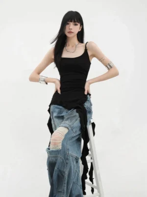 Black asymmetric ribbon-strap ruffle tank top front standing view on model wearing ripped denim and layered silver accessories showcasing fitted silhouette and design details