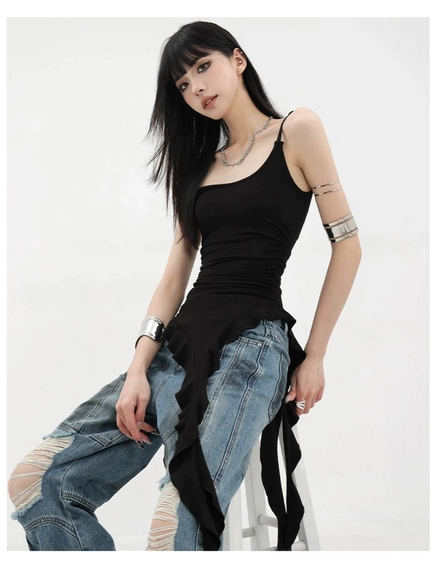 Side sitting angle view of asymmetric ribbon ruffle tank top slim fit with ripped jeans and stacked silver arm cuffs accessory styling