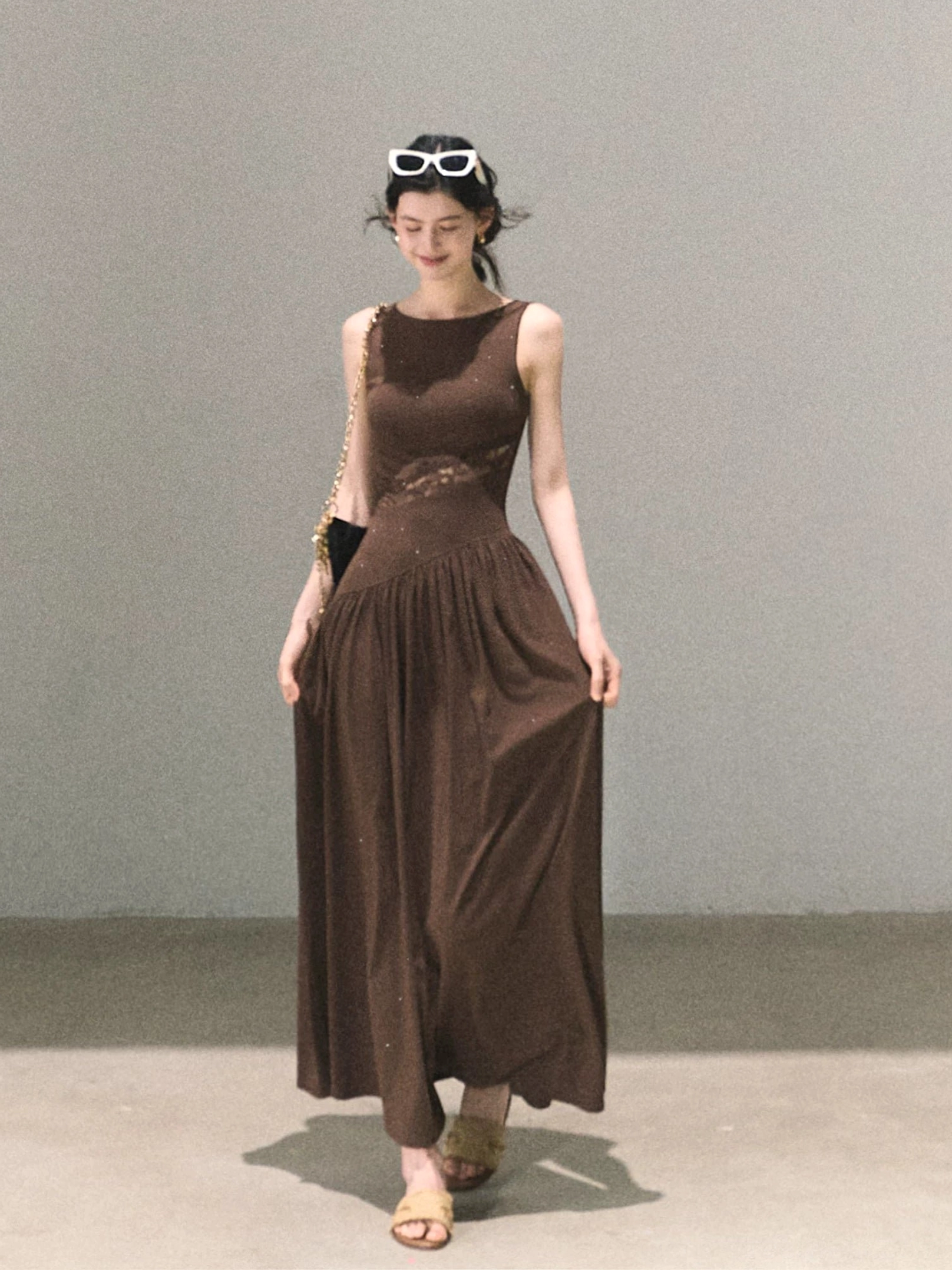 Chocolate brown asymmetrical lace waist maxi dress with sleeveless boat neckline and flowing floor-length skirt in a studio setting