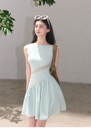 Mint blue asymmetrical lace waist mini dress with sleeveless boat neckline and flared A-line skirt styled in a minimalist studio