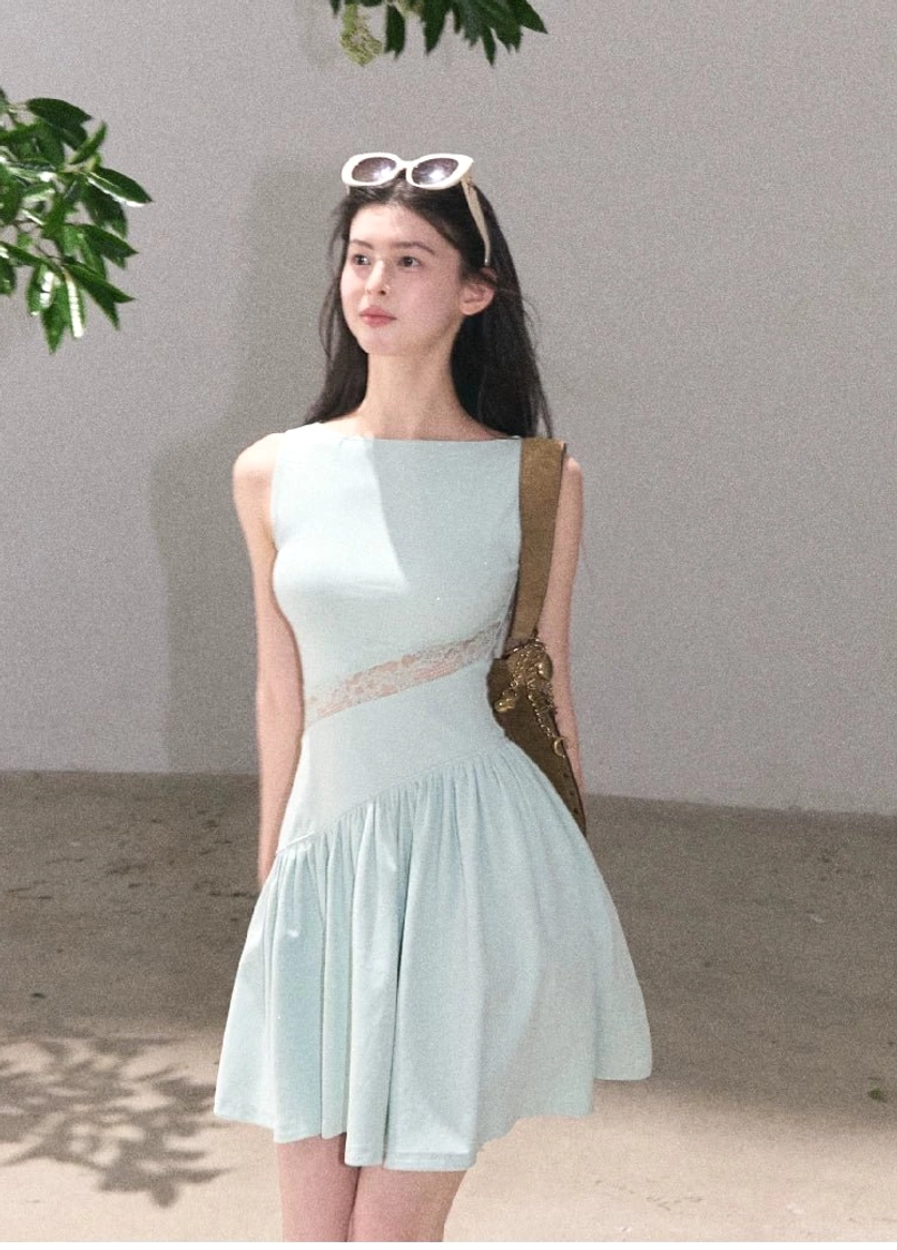 Mint blue asymmetrical lace waist mini dress with sleeveless boat neckline and flared A-line skirt styled in a minimalist studio