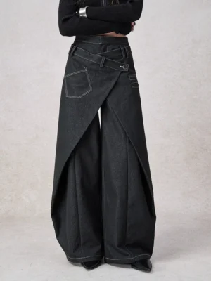 Front view of women's black asymmetrical wrap wide leg jeans with layered crossover waistband, contrast topstitching, and relaxed Y2K streetwear silhouette
