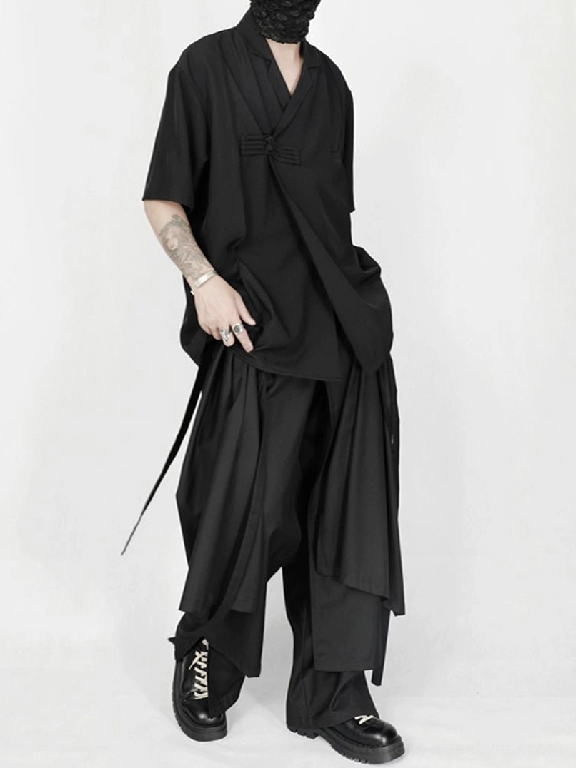 Three-quarter full-body view of avant-garde black wide-leg trousers with draped front panel and hanging side straps