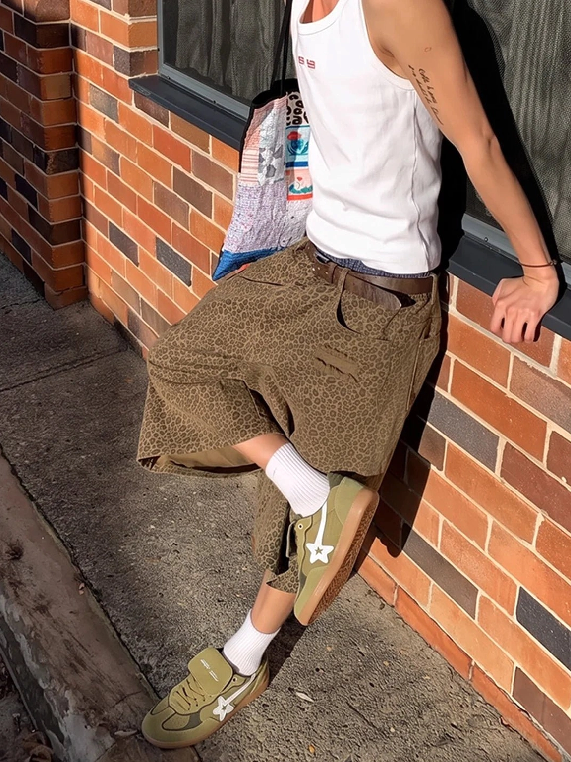 Avocado suede star-panel retro sneakers styled with cropped cargo pants and crew socks beside an urban red brick wall
