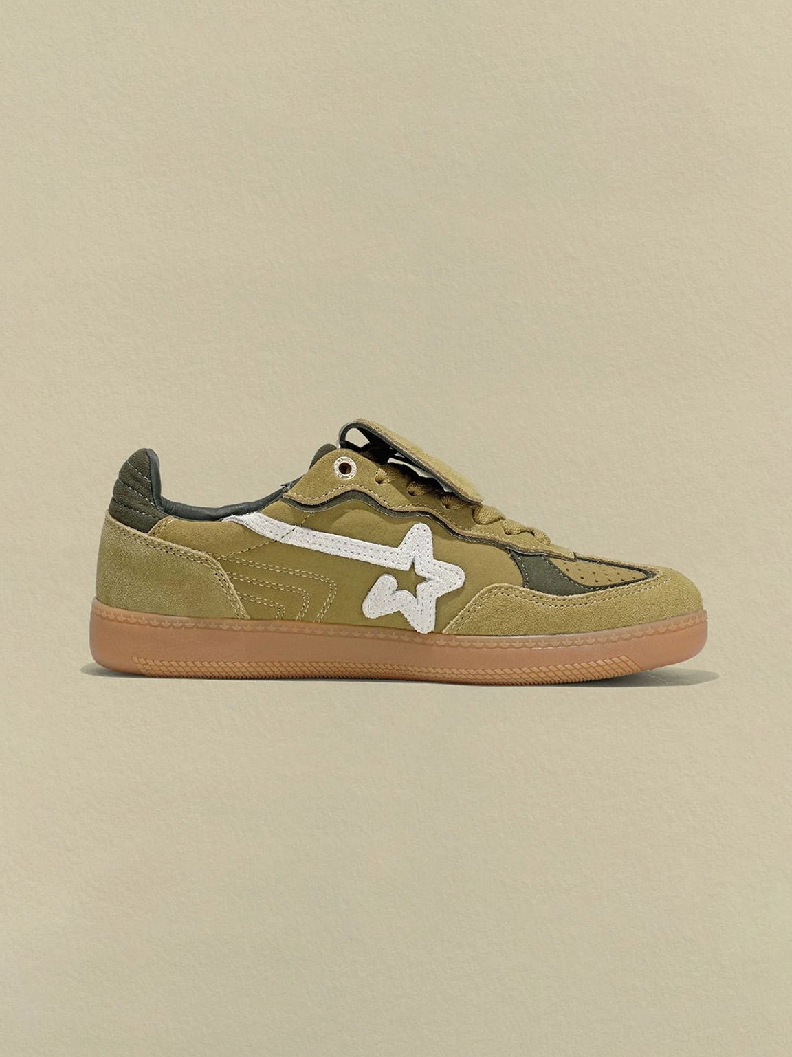 Side profile of avocado suede star-panel trainers with white side detail, dark green heel panel, and gum rubber outsole