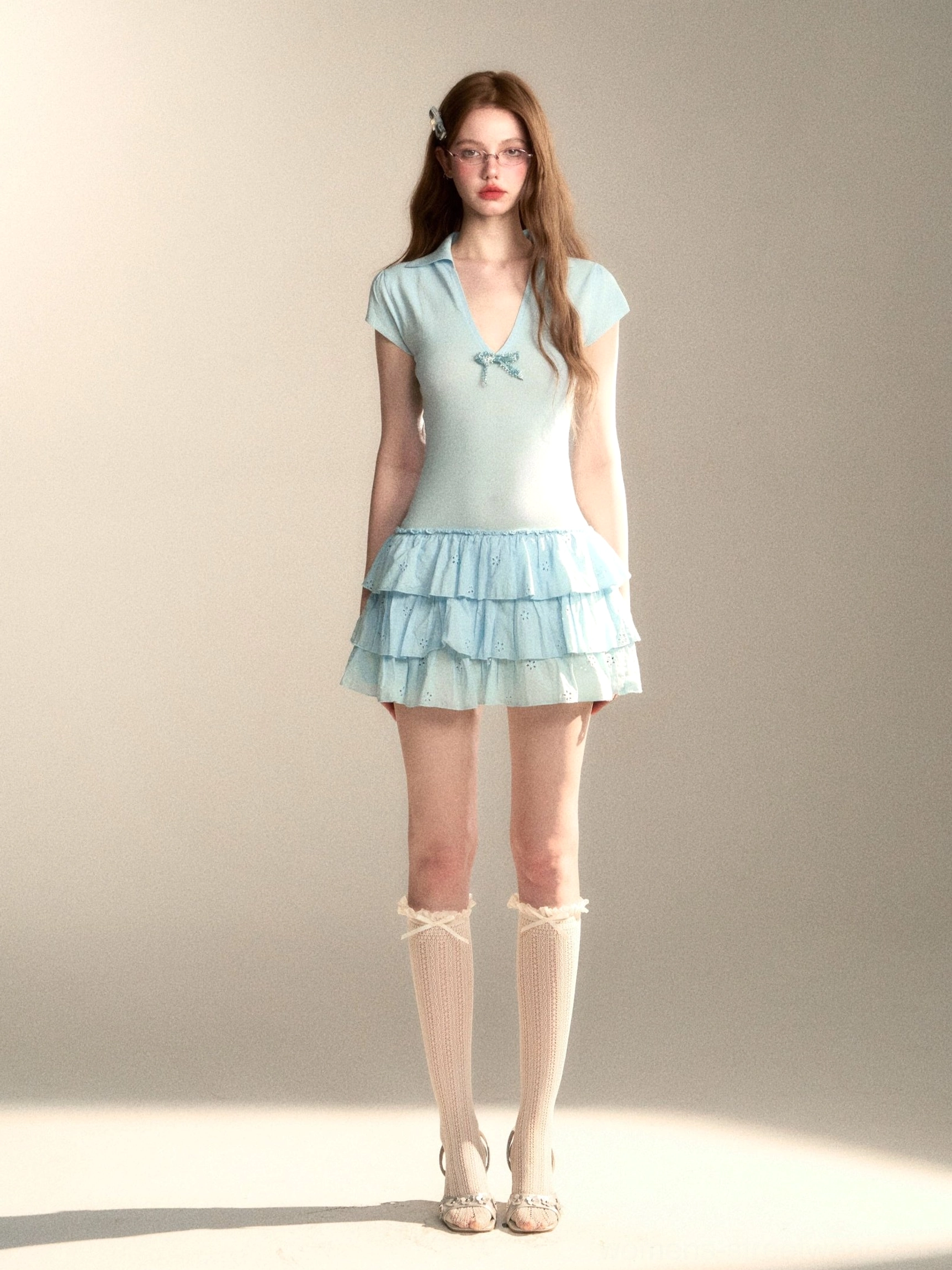 Full front view of baby blue bow detail tiered ruffle mini dress styled with lace socks and ballet flats