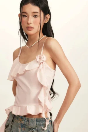 Baby pink ruffle spaghetti strap crop top with 3D floral accent and long side sash front close-up