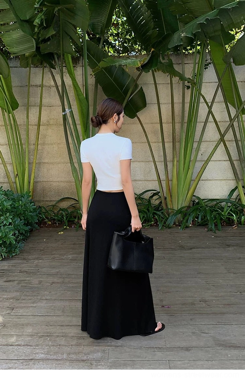 Back view of a black high-waisted flowy jersey maxi skirt styled with a cropped white top