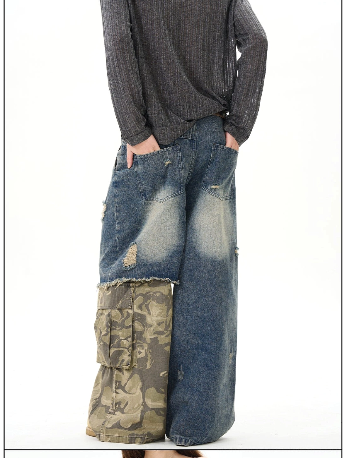 Back view of loose distressed patchwork wide-leg jeans on a male model, showing the relaxed silhouette, washed blue denim, camo lower-leg panels, and frayed ripped finish