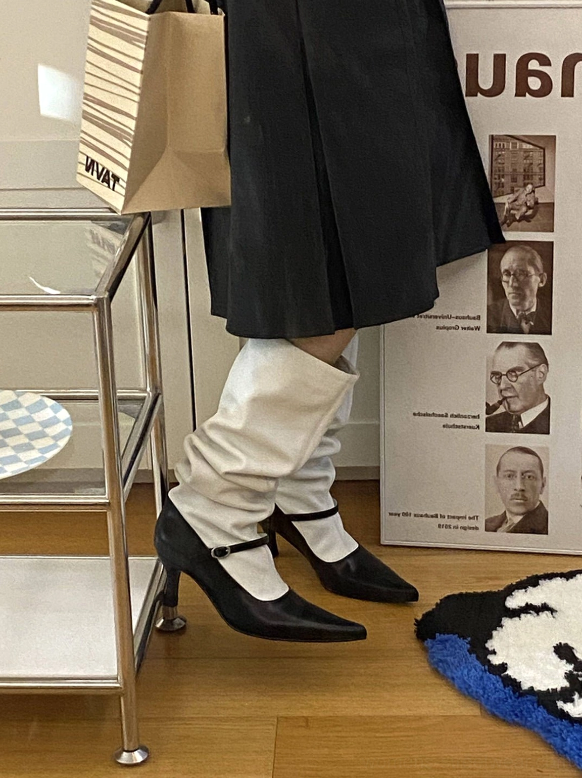 Partial back view of white slouchy knee-high boot shafts with contrasting black heels and ankle straps on a fashion model