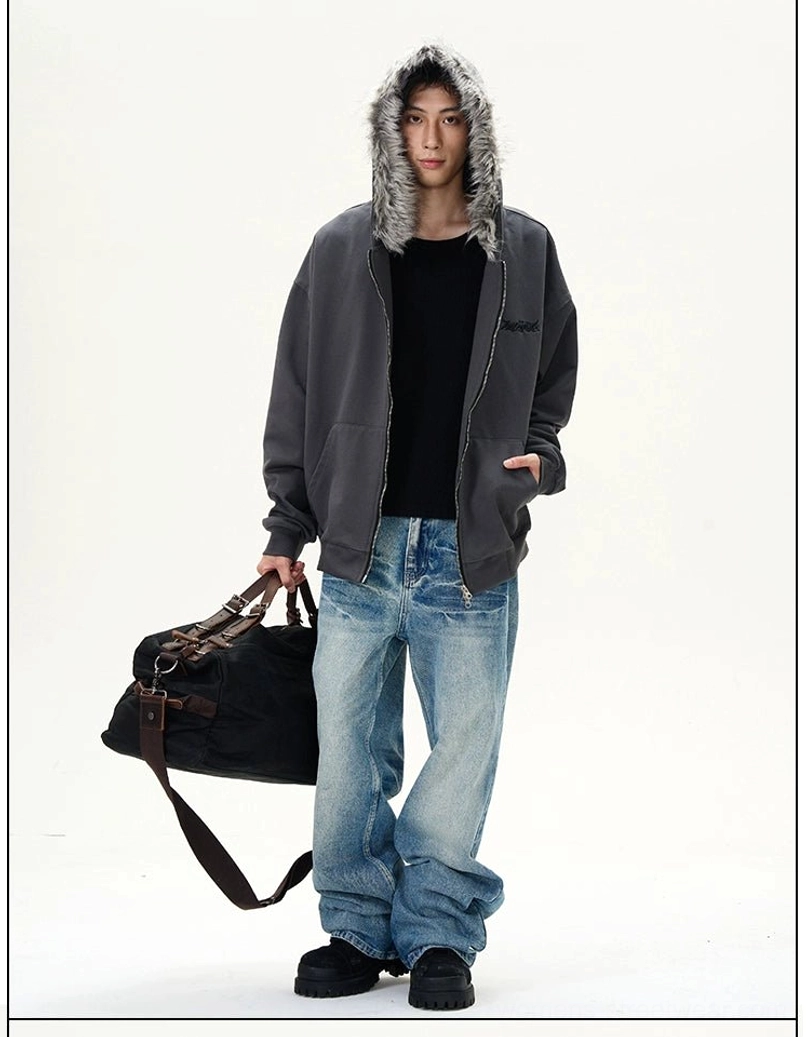 Male model wearing baggy vintage wide-leg blue jeans with a fur-trimmed hoodie and travel bag