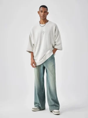 Baggy wide-leg denim jeans shown in a full front view with washed blue finish, oversized crewneck t-shirt, and casual Seoul streetwear styling