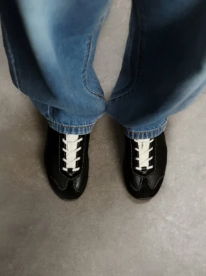 Black ballet-inspired slim leather-look trainers worn with blue straight-leg denim in top-down streetwear outfit view