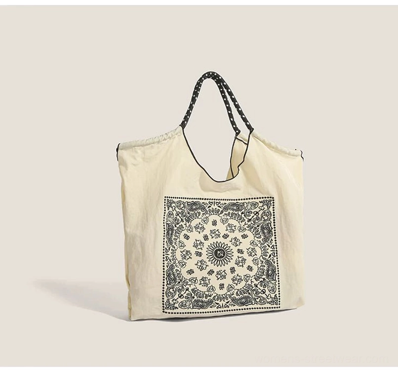 Off white bandana paisley drawstring market tote bag with black dotted shoulder straps front studio view