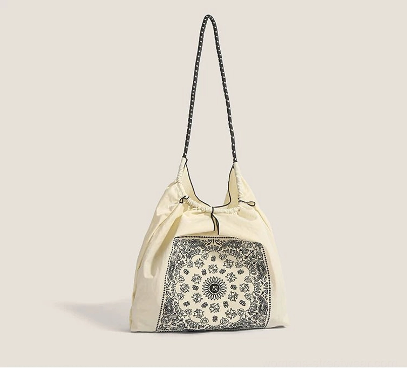 Side profile of off white paisley drawstring market tote bag with adjustable top and contrast shoulder strap