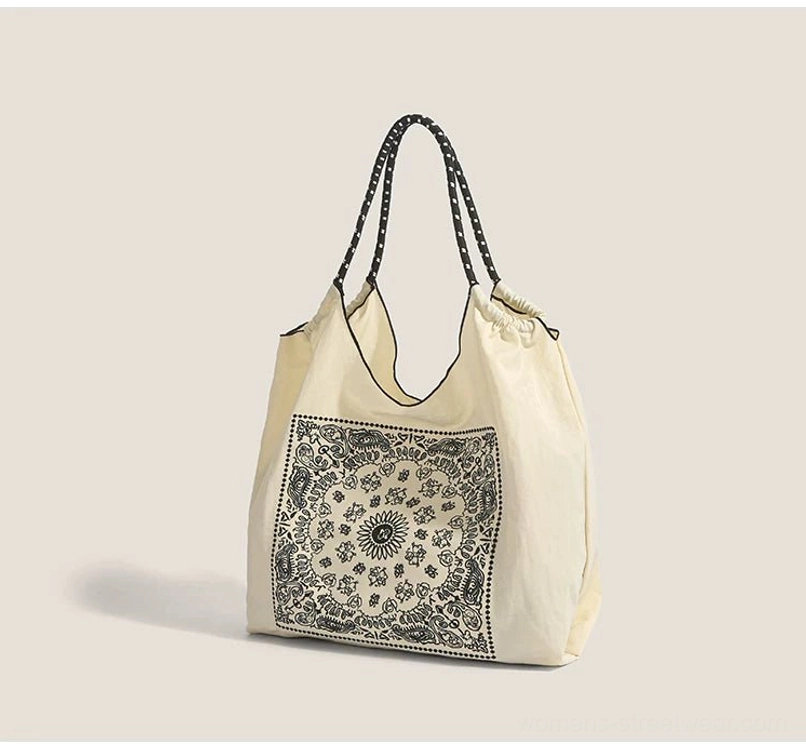 Three quarter view of off white bandana paisley market tote with drawstring top and black dotted handles