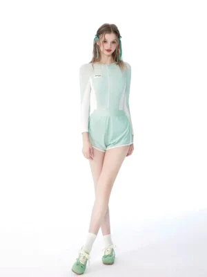 Bean green sporty swim romper set shown from a three-quarter front angle with long sleeves, white contrast panels, half-zip front, and high-waisted shorts