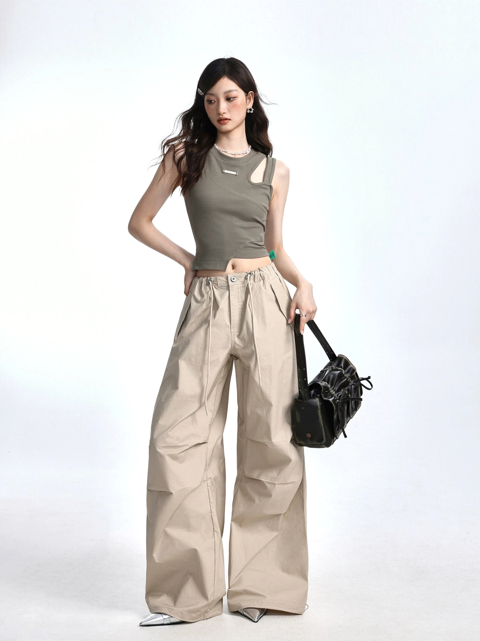 Bean Paste Green asymmetric cutout ribbed crop tank front view styled with khaki wide leg cargo pants and black ruched shoulder bag