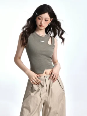 Close-up of Bean Paste Green ribbed asymmetric crop top with one shoulder cutout irregular curved hem and metal chest badge