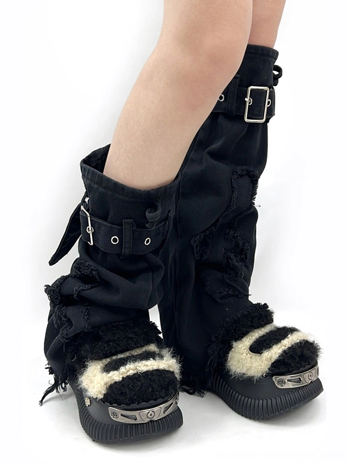 Front three-quarter view of beige and black fuzzy platform sneakers styled with black combat leg warmers and silver metal toe caps