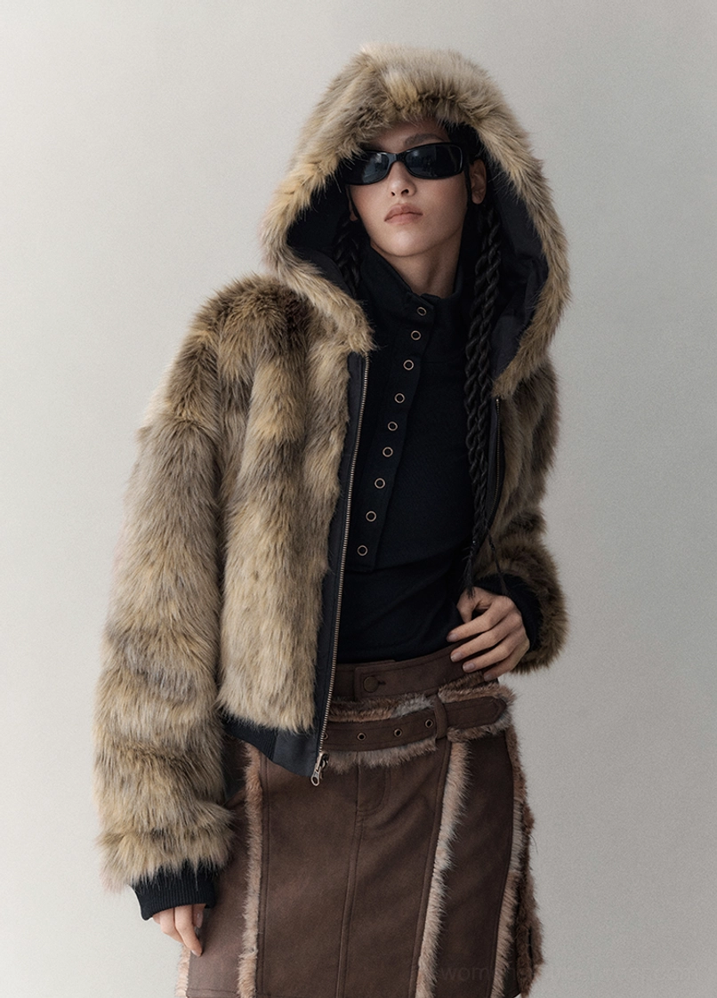 Model wearing the full beige brown faux fur side of a cropped reversible hooded winter jacket with plush texture and zip front