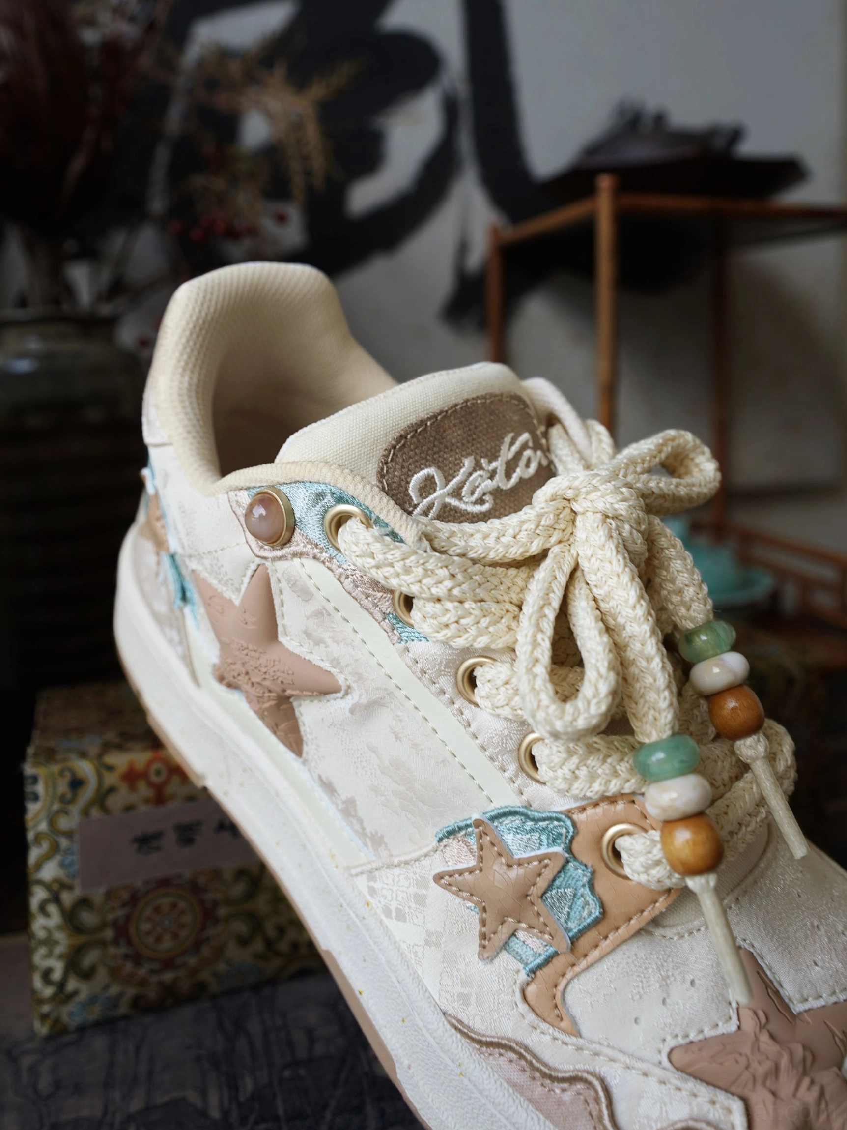 Beige and brown star panel sneakers with vintage court silhouette, teal accents, and decorative rope laces