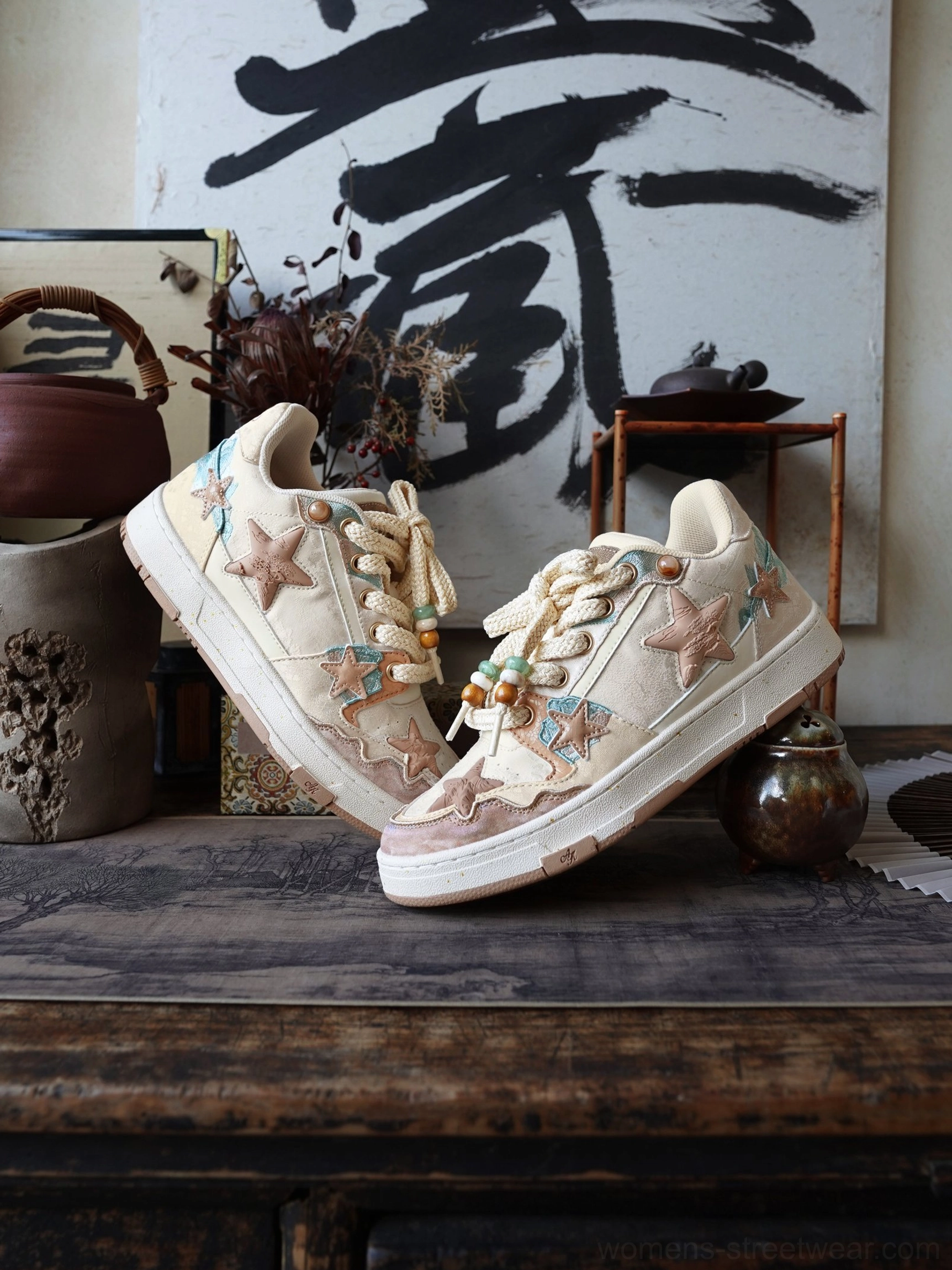Low-angle close-up of beige and brown star patterned court sneakers with beaded rope laces and layered star patches