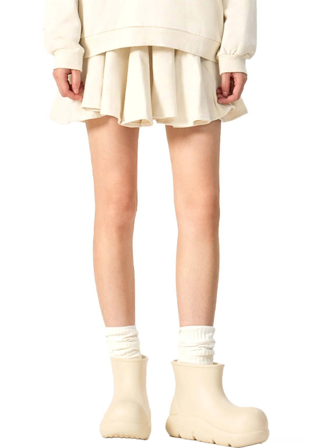 Beige chunky short rain boots styled with white crew socks ruffled mini skirt and cropped sweatshirt