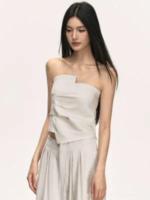 Close-up of beige cropped strapless wrap top with asymmetric folded neckline and twisted front detail