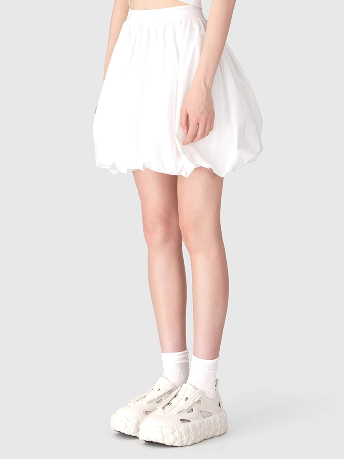 Front view of beige cutout platform sandals paired with white socks and a clean monochrome mini skirt outfit