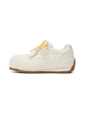 Beige double-lace low-profile retro streetwear trainers with yellow laces and gum rubber outsole front side studio view