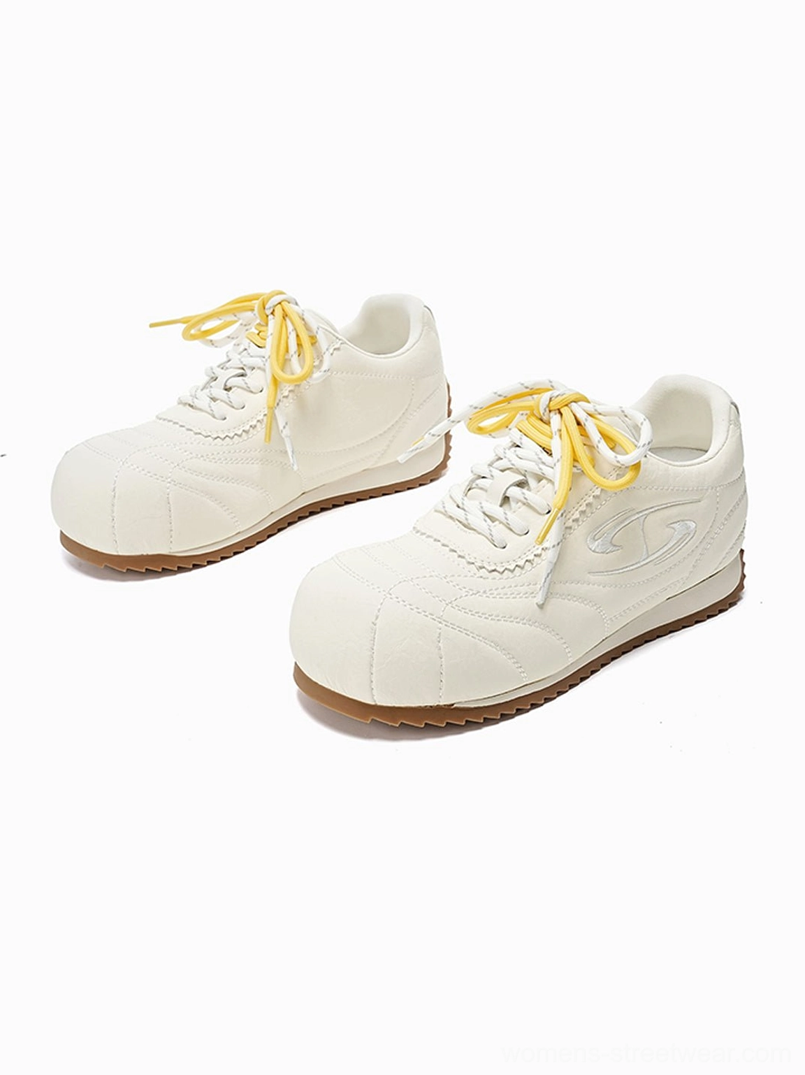 Pair of beige double-lace low-profile retro trainers with yellow laces and brown gum soles on white background