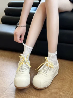 Beige low-profile retro trainers worn with frilled white ankle socks in an everyday Korean streetwear outfit