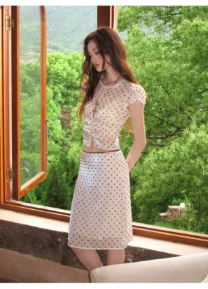 Side view of fitted beige polka dot mesh two piece outfit with cropped top and elegant midi skirt