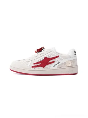 Beige and red retro training sneaker shown in a side-front product view with layered suede panels, red flame side graphic, flower lace ornament, and red rubber outsole